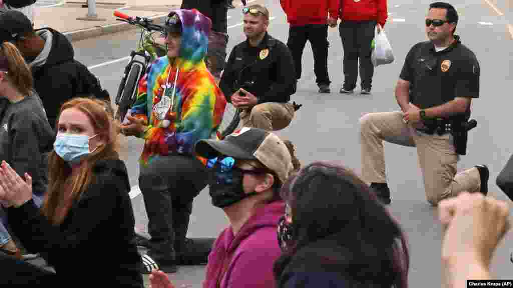 Лейтенант Алекс Рено, з поліцейсьного відділку міста Гемптон (праворуч), та заступник шефа поліції Кевін Ґелано, з поліцейсьного відділку міста Сібрук (посередині), приєдналися до протестувальників та опустилися на коліно на пляжі у Гемптоні. Люди вимагають справедливості щодо факту загибелі Джорджа Флойда. Гемптон, штат Вірджинія. 1 червня 2020 року (Фото AP/Charles Krupа)