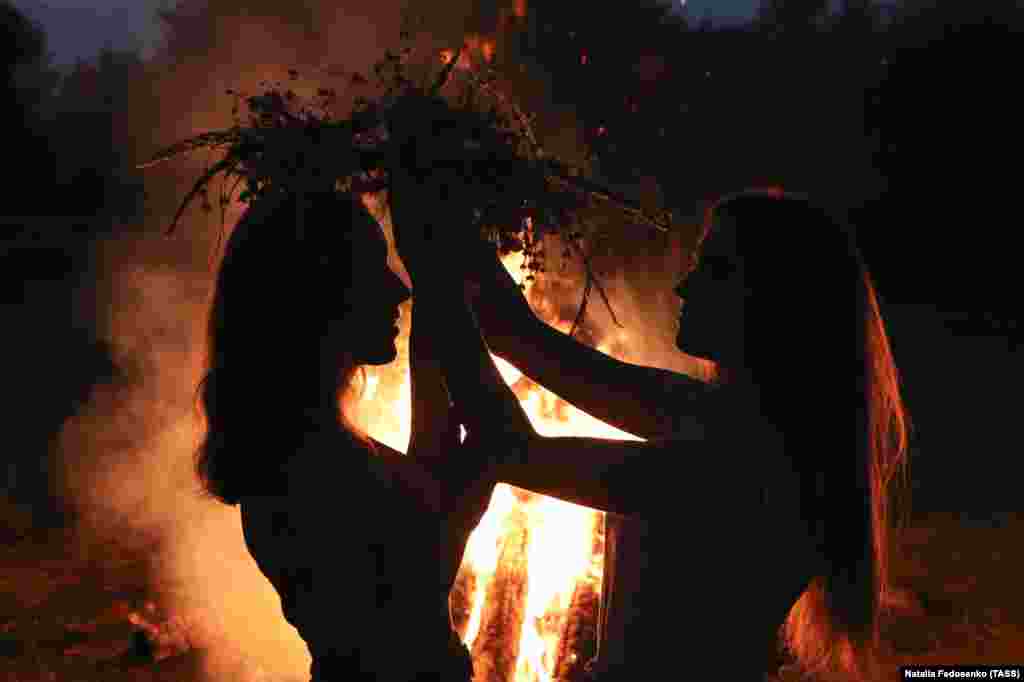 Дівчата одягають на голову вінки біля купальського  багаття. Під час святкування Івана Купала на березі річки Прип'ять. Гомельська область Білорусі, 6 липня