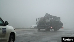 The damaged vehicle that drove over a land mine while transporting members of the OSCE, killing one and injuring two, is moved from the scene of the tragic incident on April 23.
