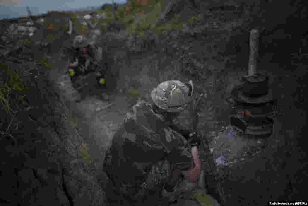 Солдат батальйону «Донбас» розпалює вогонь у буржуйці, яка служить як для обігріву, так і для приготування їжі на передовій