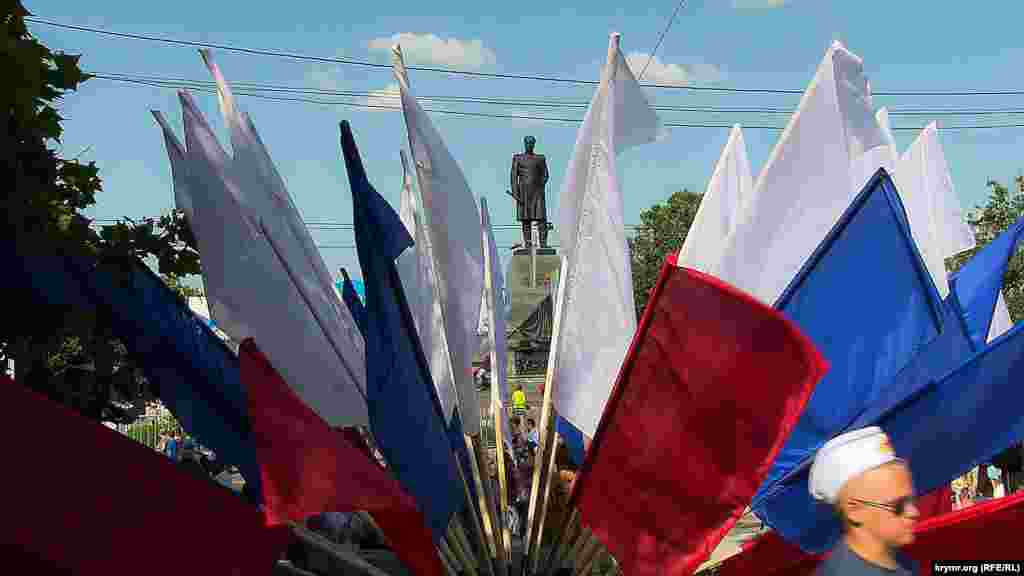 Крізь «букет» із прапорів видніється пам'ятник Нахімову