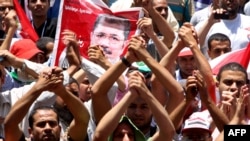 Supporters of the Muslim Brotherhood's presidential candidate Muhammad Morsi hold his portrait during a demonstration on Cairo's Tahrir Square