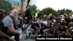 Поліцейські опустилися на коліно разом з протестувальниками під час акції протесту через загибель після затримання поліцією афроамериканця Джорджа Флойда, Атланта, 1 червня 2020 року