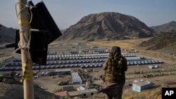 Un luptător taliban stă de gardă deasupra unei tabere de refugiați afgani repatriați din Pakistan, în mai 2025.