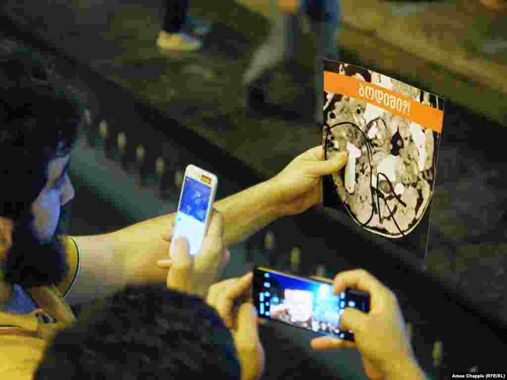 Protesters hold up pictures of a medical scan, which they say is of an activist's skull in which a rubber bullet is embedded.