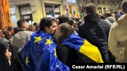 Pristalice Nikusora Dana, dvoje zamotnih u zastave EU i Rumunije, iščekuju rezultate drugog kruga predsedničkih izbora na skupu u Bukureštu, 18. maja 2025.