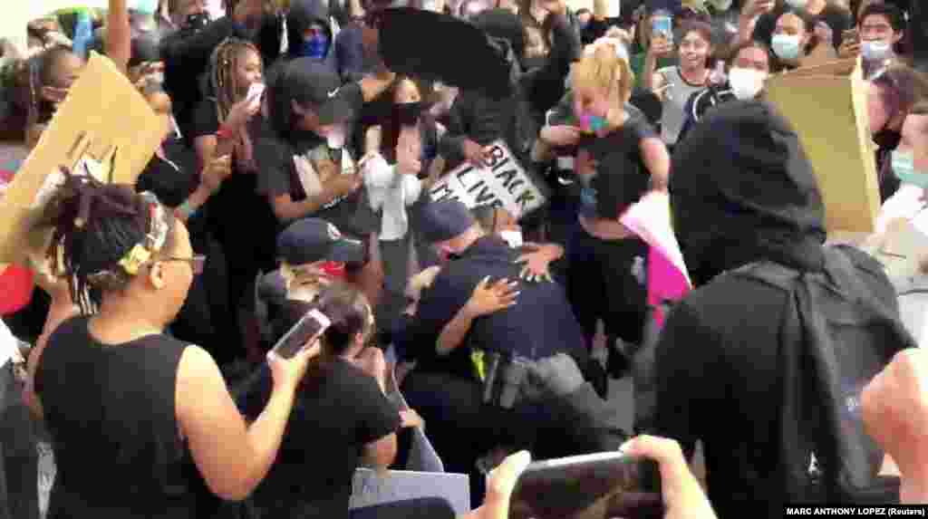 Шеф поліції міста Оклі Ерік Крістенсен обіймає протестуючого, стоячи на колінах перед протестувальниками. Оклі, штат Каліфорнія. (Фото з відео зі соцмереж. MARC ANTHONY LOPEZ /via REUTERS)