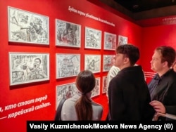 Vizitatorii privesc schițe propagandistice care arată trupele nord-coreene luptând împotriva ucrainenilor.