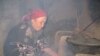 A Tajik woman cooks food over an open fire due to lack of electricity.