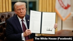 Президент США Дональд Трамп демонстрирует один из указов, подписанных им после инаугурационных торжеств 20 января