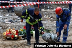 Echipele de intervenție poartă un fragment dintr-o rachetă de croazieră rusească Iskander-K care a lovit o clădire rezidențială din Kiev pe 1 august.