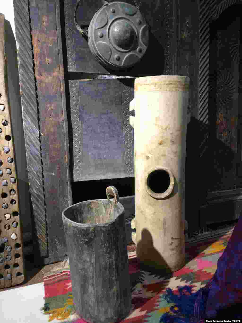 На переднем плане – деревянная мера для зерна, сзади – маслобойка (ее прикрепляли к высокому месту и качали)