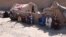 An internally displaced Afghan family sits outside a temporary shelter as they await relief from the authorities on the outskirts of Herat.