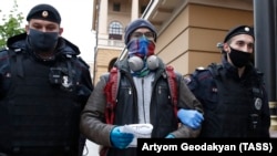 Police officers lead away a man performing a single-person picket in front of the Moscow City Police headquarters in July.