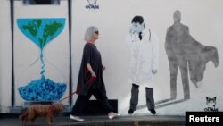 زنی در ویتستبل بریتانیا در حال عبور از برابر دیوارنگارهای درباره کرونا